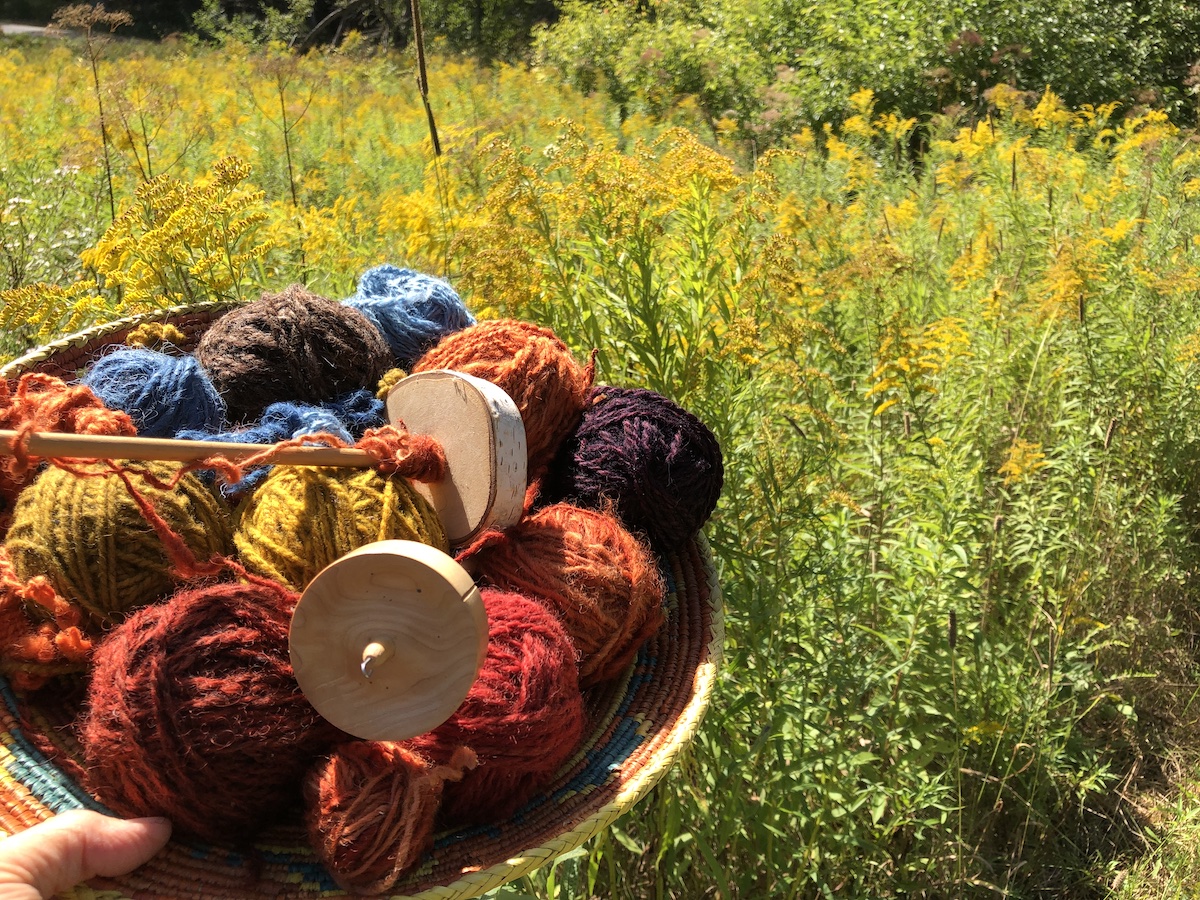 basket of colorful balls of yarn with a field of goldenrod behind