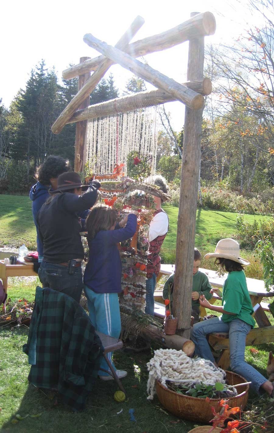 family weaving on a large loom outdoors