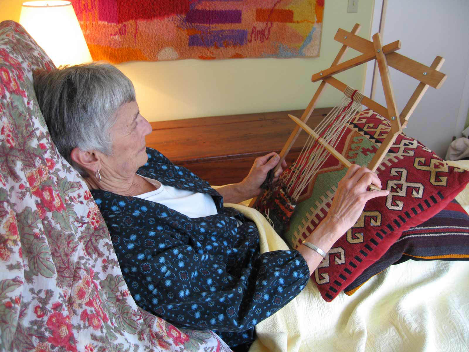 woman in bed with small loom